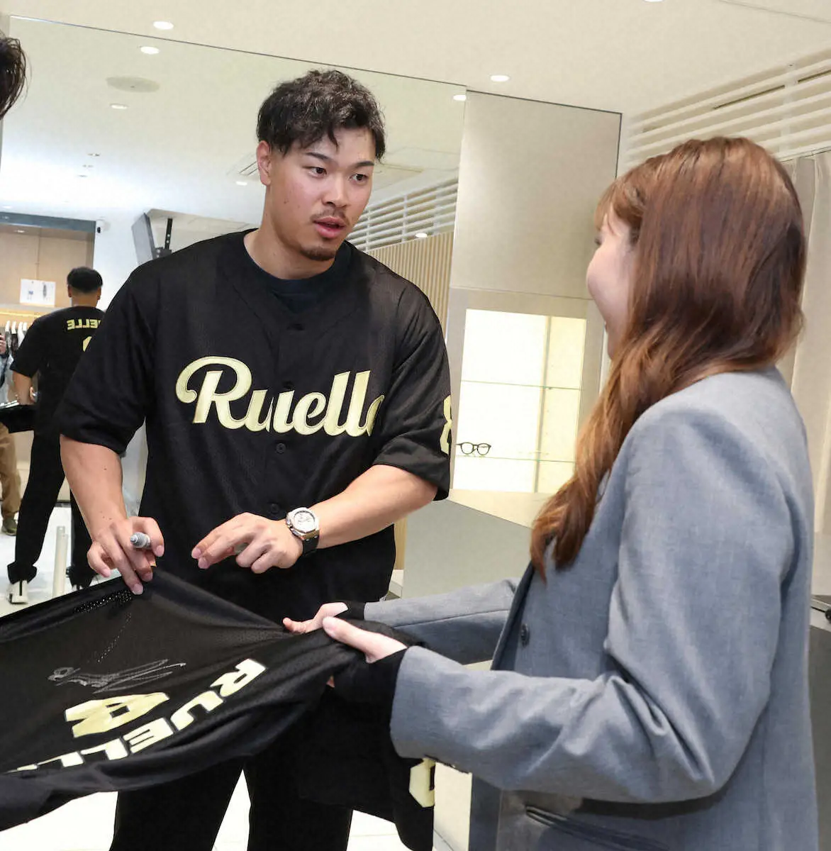 RUELLEの半日店長を務めコラボ商品購入者にサインする佐藤輝（撮影