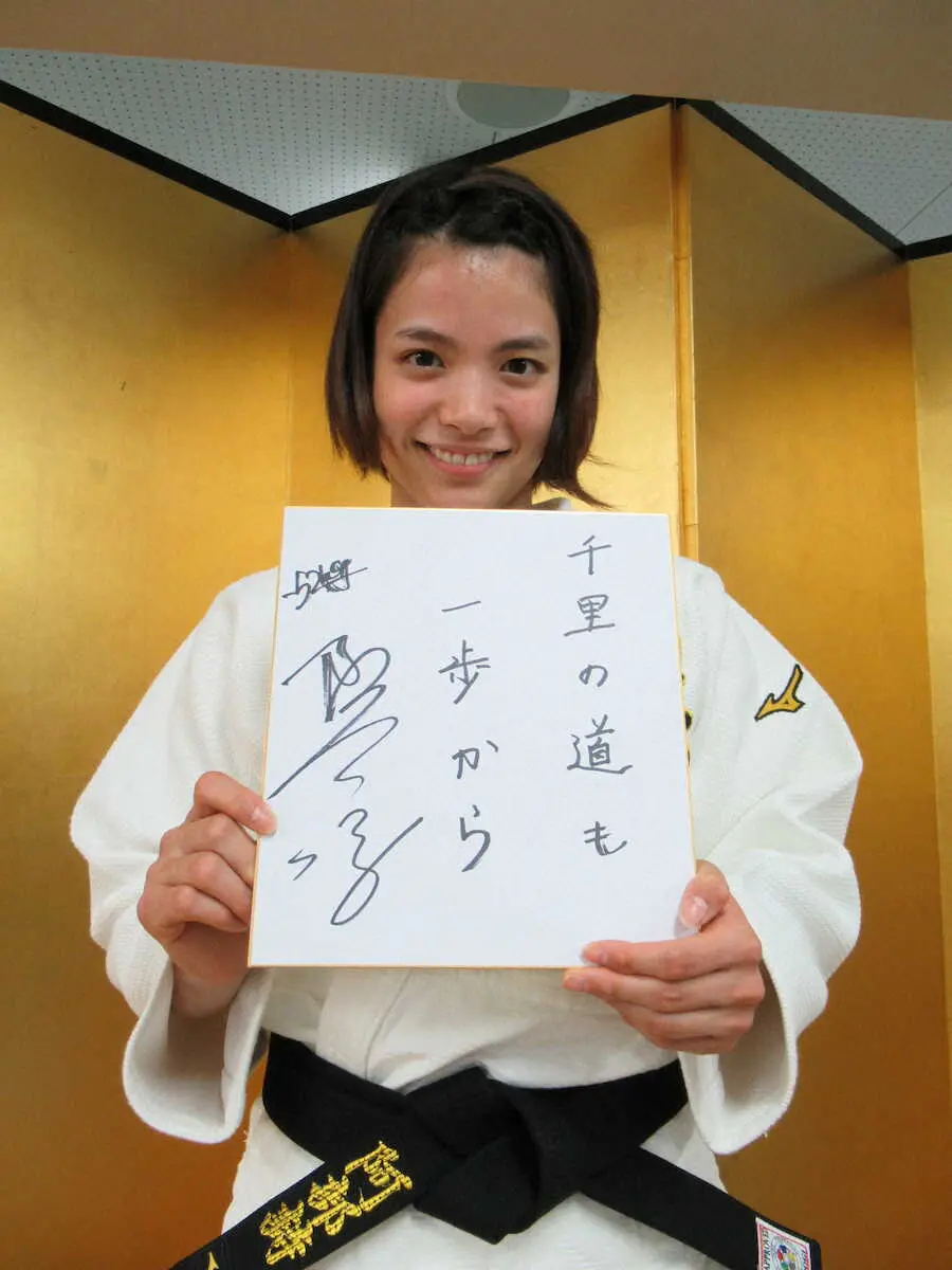 大切にしている言葉「千里の道も一歩から」と書き込んだ色紙を手に撮影