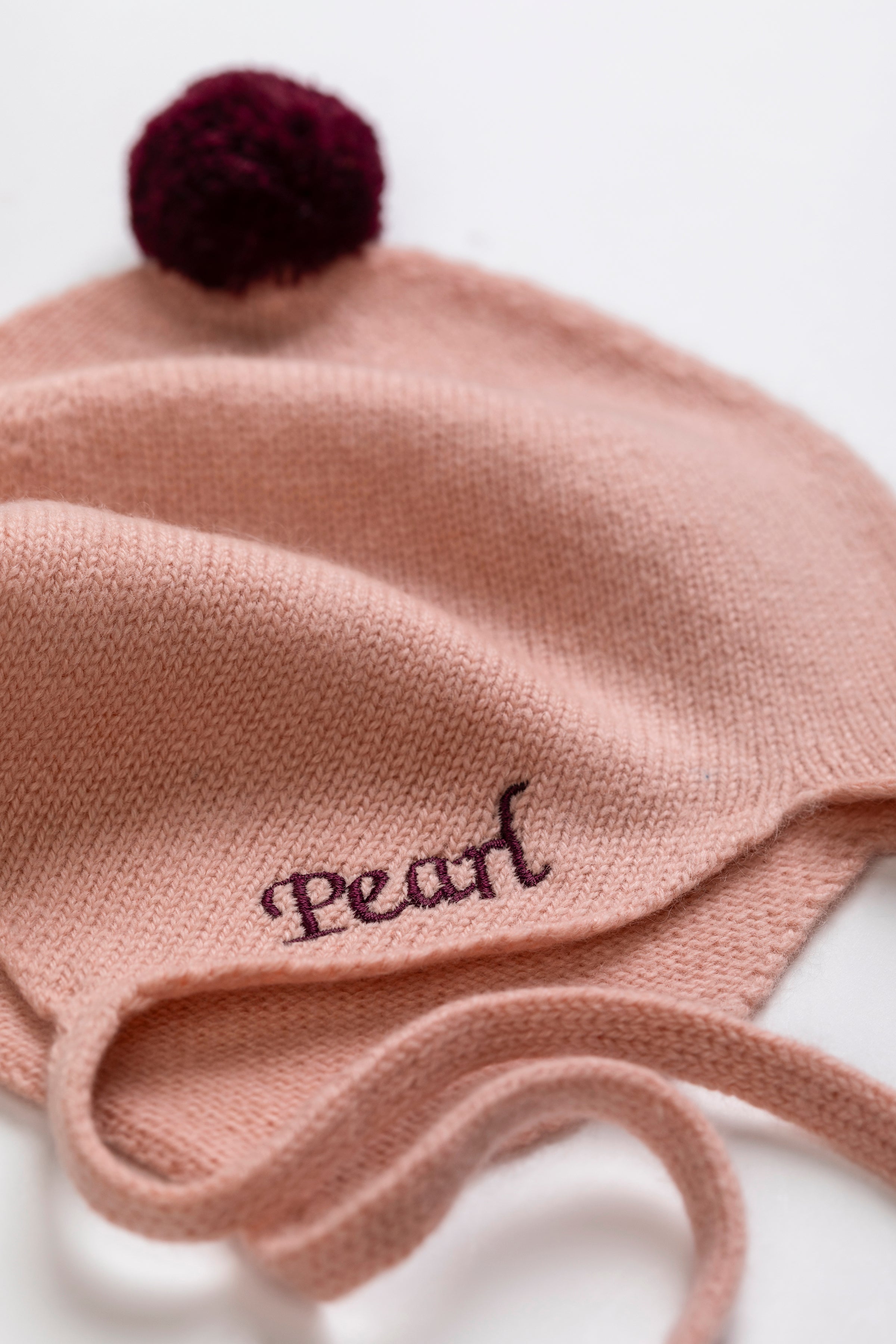 Rosie Sugden Cashmere's Baby Bonnet in Coral with Damson Pom-Pom